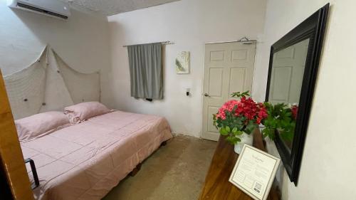 a small bedroom with a bed and a vase of flowers at Casa bugambilias in Troncones