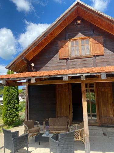 a large wooden house with a porch with chairs at Aphrodite Hills Apartments-Stara Planina in Crni Vrh