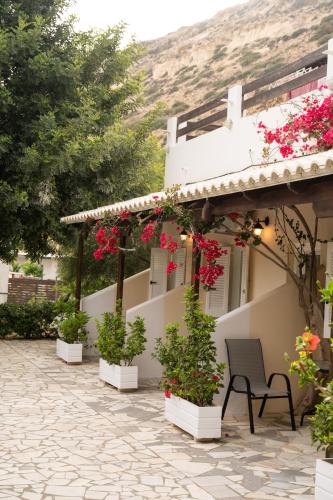 a patio in front of a house with flowers at Pension Romantika in Matala