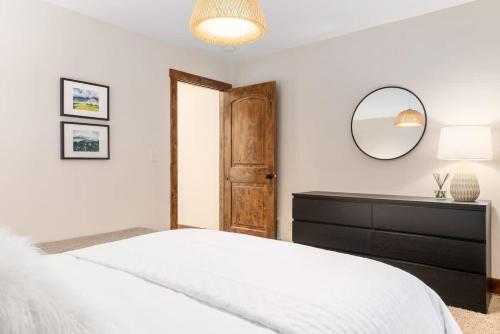 a bedroom with a bed with a dresser and a mirror at Stylish Mtn Home Fireplace Views in Victor
