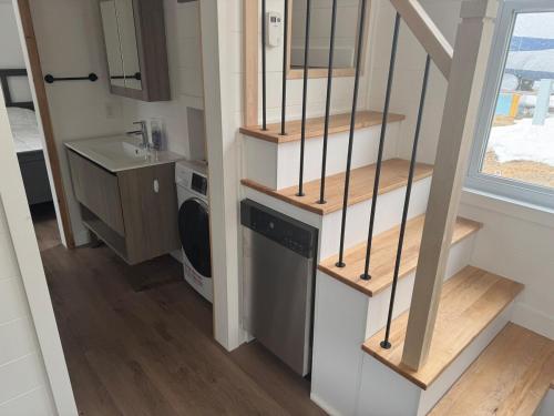 a tiny house with a staircase and a washing machine at Le Grand Héron - Mini-maison à St-Zénon in Saint Zenon