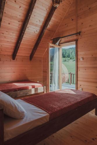 two beds in a wooden room with a window at Arhetip, Kikina Villa in Njegovuđa