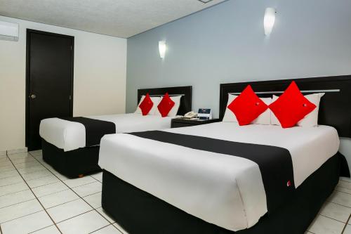 two beds in a hotel room with red pillows at Capital O Hotel Victoria Morelia in Morelia