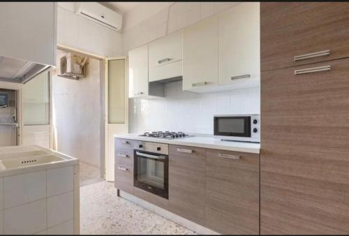 a white kitchen with a stove and a microwave at Aura apartaments in Torre Lapillo