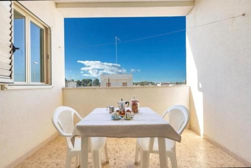 a white table and chairs in a room with a window at Aura apartaments in Torre Lapillo