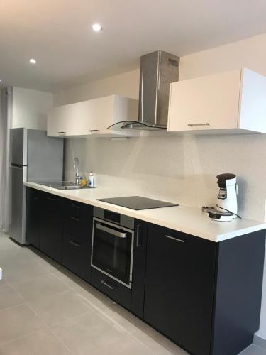 une cuisine avec des armoires noires et des comptoirs blancs dans l'établissement Studio La grande Motte, à La Grande Motte