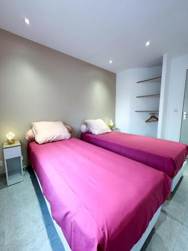 deux lits dans une chambre avec des draps roses dans l'établissement La SébaïaVie, à Sète
