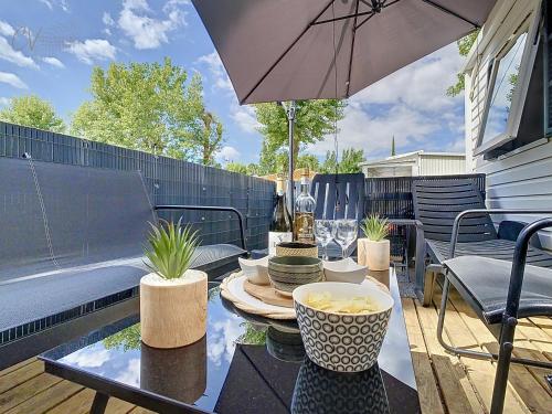 un patio avec une table et un parasol dans l'établissement Mobil-Home MA 62 à Vias - La Carabasse - Camping Siblu avec piscine, à Vias