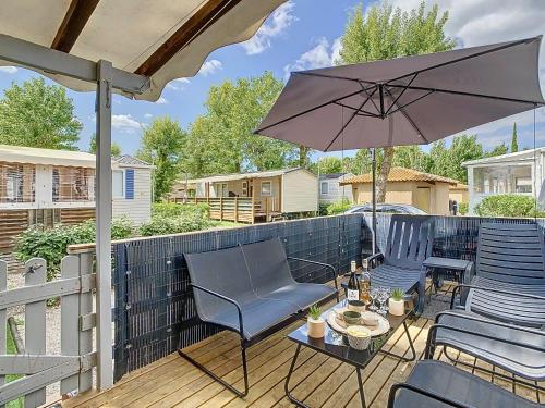 un patio avec des chaises et un parasol sur une terrasse dans l'établissement Mobil-Home MA 62 à Vias - La Carabasse - Camping Siblu avec piscine, à Vias