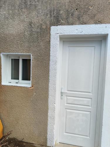 a white door and a window on the side of a building at Studio plain-pied entrée privée et parking gratuit in Le Passage