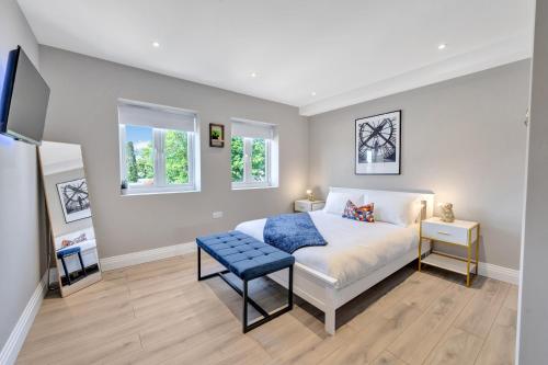 a bedroom with a bed with a blue stool and two windows at Travard at Heathrow 386a in Harmondsworth