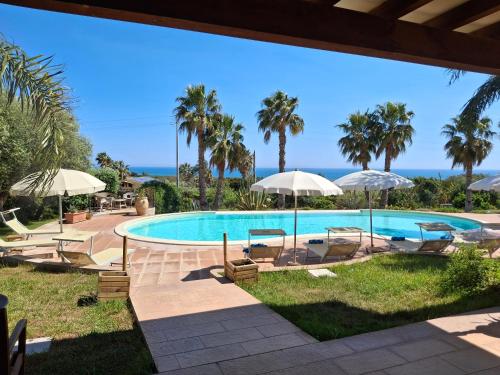 a swimming pool with chairs and umbrellas at L'Oasi del Mediterraneo in Sampieri