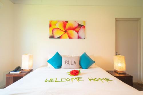 a bedroom with a bed with a welcome home sign on it at First Landing Beach Resort & Villas in Lautoka