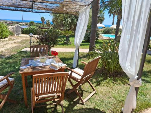 a table and chairs in a yard with a view of the ocean at L'Oasi del Mediterraneo in Sampieri