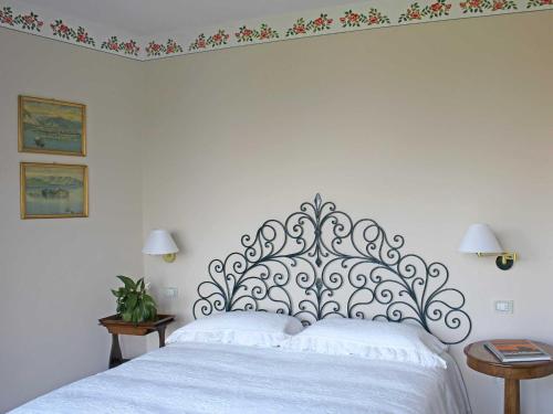 a white bed with a metal headboard in a bedroom at Villa Rubino Apartment con giardino e jacuzzi vista lago in Stresa