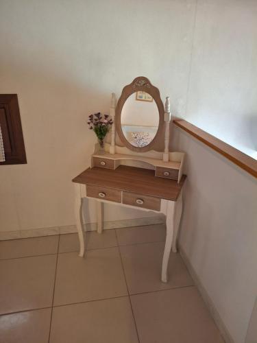 a dressing table with a mirror and a vase of flowers on it at L'Oasi del Mediterraneo in Sampieri