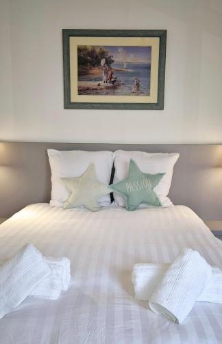 - un lit blanc avec des oreillers et une photo sur le mur dans l'établissement La Maison des Piranhas, à Arcachon