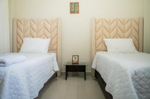 a bedroom with two beds and a side table at El Hogar de Olguita - Departamento Deluxe in Tarapoto