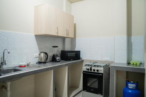 a small kitchen with a sink and a stove at El Hogar de Olguita - Departamento Deluxe in Tarapoto
