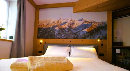 a bedroom with a bed with a painting on the wall at Da Gigi Alpine Rooms in Crandola Valsassina