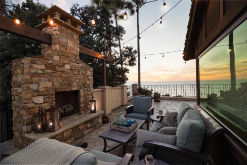 an outdoor patio with a stone fireplace and chairs at Oceanfront Luxury Home Sunset Views in San Diego