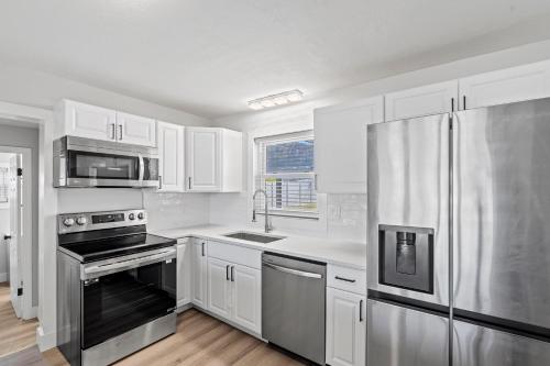 a kitchen with white cabinets and stainless steel appliances at Palms Retreat in Central Largo - mins to the Sand! in Largo