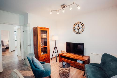 a living room with two chairs and a flat screen tv at CBlue "Zickerstuuv", Wasserblick, in der Natur, Grill in Groß Zicker