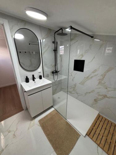 ein Badezimmer mit Dusche, Waschbecken und Spiegel in der Unterkunft Villas Sossego in Porto Santo