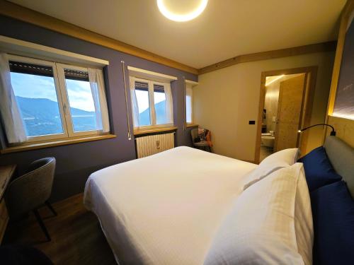 a bedroom with a large white bed and two windows at Da Gigi Alpine Rooms in Crandola Valsassina