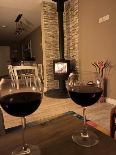 two glasses of wine sitting on a table with a fireplace at Ardnageeha in Doagh