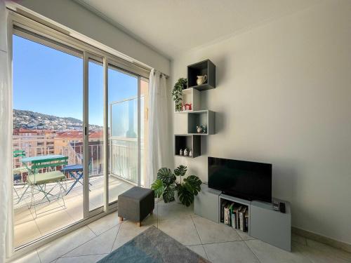 un salon avec une télévision et une grande fenêtre dans l'établissement Risso - charming one bedroom with a balcony, à Nice