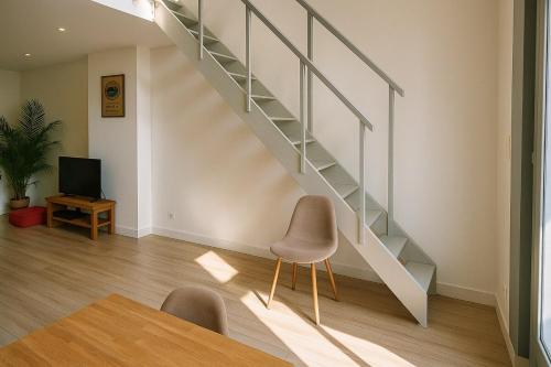 a staircase in a living room with a table and a chair at Joli T2 esprit LOFT in Loos