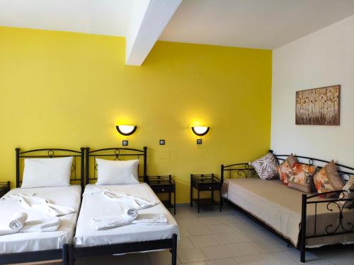 two beds in a room with yellow walls at Evelin hotel in Pythagoreio