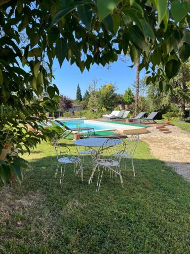 a table and chairs in the grass near a pool at Gîte Villa Santina in Piquecos