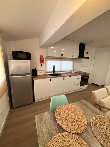 a kitchen with white cabinets and a table and a refrigerator at Villas Sossego in Porto Santo