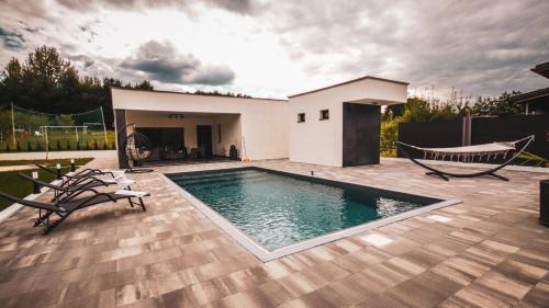 a swimming pool on a patio with chairs and a house at Villa Eden Bihać in Bihać
