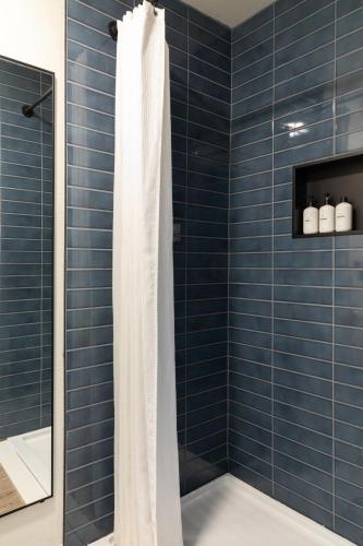 a blue tiled shower with a white shower curtain at LOGE Leavenworth - Downtown in Leavenworth