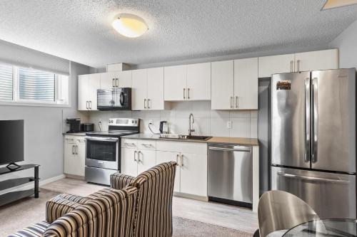 a kitchen with white cabinets and a stainless steel refrigerator at Spacious 2BR Suite - SW Edmonton in Edmonton