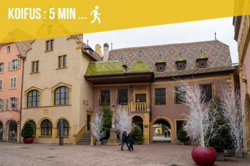 2 personnes marchant devant un bâtiment dans l'établissement Bretzel Bed Petite Venise Bed in Shared room City Center Wi-Fi, à Colmar