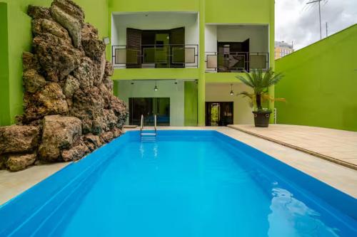 a large swimming pool in a house with a building at Quarto privativo 5 minutos metrô com Piscina e churrasqueira in Sao Paulo