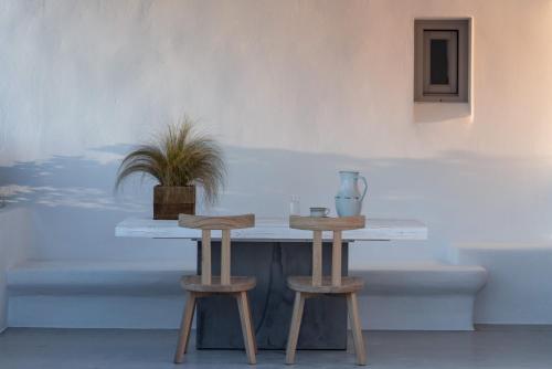 a table and two stools in front of a wall at Seven Suites in Glinado Naxos