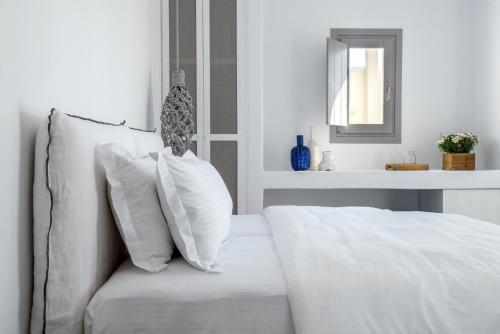 a white bed with white pillows and a mirror at Seven Suites in Glinado Naxos
