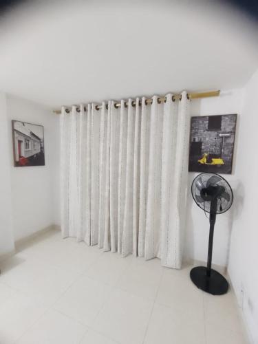 a room with white curtains and a fan at Hermoso apartamento cerca al Poblado in Medellín