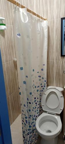 a bathroom with a toilet and a shower curtain at Hostal Bosque de Niebla in Salento