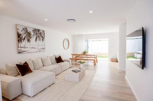 a white living room with a couch and a table at Olas Villa 4 - Plunge Pool & Walk to Beach in Anna Bay