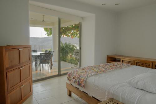 a bedroom with a bed and a balcony with a table at Condos Cruz del Mar in Santa Cruz Huatulco