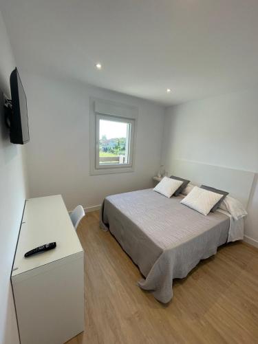 a white bedroom with a bed and a window at Casa Galbán in Vilagarcia de Arousa