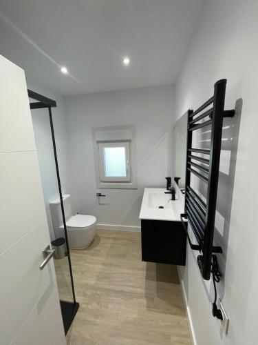 a white bathroom with a sink and a toilet at Casa Galbán in Vilagarcia de Arousa