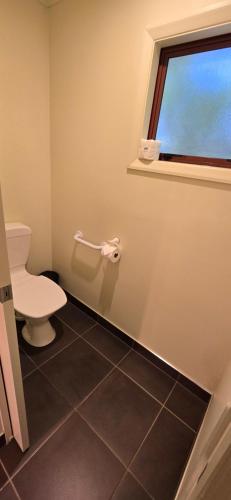 a bathroom with a toilet and a window at The Rocks Chalets in Takaka