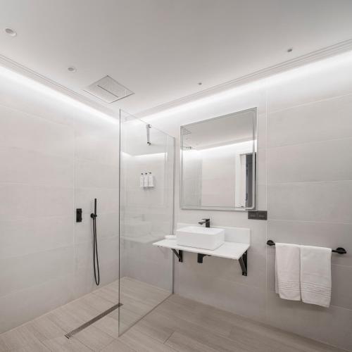 a white bathroom with a sink and a shower at Casa ART Sevilla in Seville